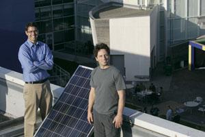 Andrew Beebe, of EI Solutions, left, and Sergey Brin, of Google, stand next to a solar panel set up on a rooftop.