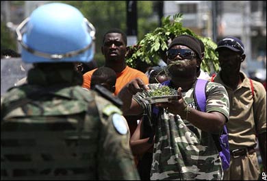 A demonstrator eats grass in front of a U.N. peackeeping soldier in Port-au-Prince
