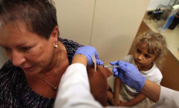 Sharyn Epling, 5, watches as her grandmother, Sharon Alvarez, receives a flu shot from Maria Bucio, an Advanced Registered Nurse Practitioner on September 2.