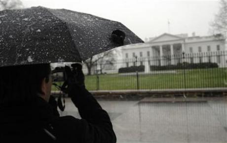A light snow settles on a tourist's umbrella as he takes a picture