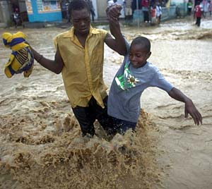 People wade through a flooded street in Léogâne, Haiti.