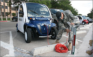 Photo of a man in a uniform plugging an electric car into an outlet