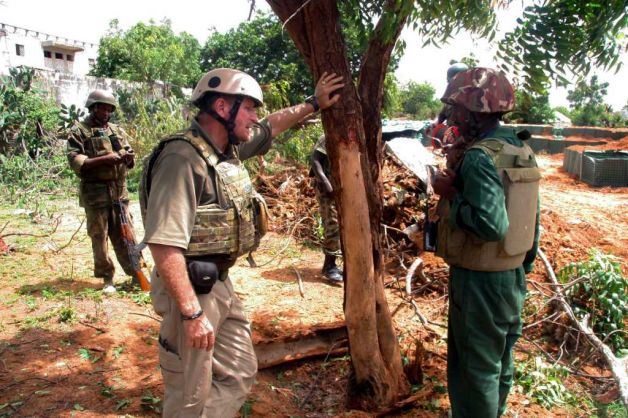 In this Tuesday Aug. 9, 2011 photo, explosives expert Martinus Van Blerk, left, and a team of Ugandan soldiers are seen just after blowing up a hand grenade left behind by Islamist rebels in the Somali capital of Mogadishu on Tuesday. The force of the explosion stripped the bark from a nearby tree and blew up six sandbags. On the front lines of Mogadishu's street battles, Somali fighters and foreign militants square off against soldiers from Uganda and Burundi. Standing alongside them, quietly giving advice, is an American-run team of former military men who are helping the African Union troops defeat al-Shabab. Photo: Katharine Houreld / AP