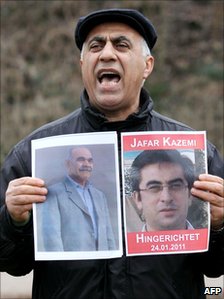 A protester in Hamburg, Germany holds up pictures of Iranian opposition activists Jafar Kazemi and Mohammad Ali Hajaghaei who were hanged in Iran, 24 January 2011