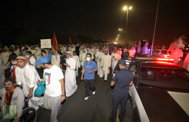 Kuwaiti opposition supporters march along a major road in Kuwait City on November 4, 2012, as policemen monitor during a demonstration against the decision by Emir Sheikh Sabah al-Ahmad al-Sabah to amend the electoral law despite it having been confirmed by a court last month. (AFP Photo/Yasser Al-Zayyat) 