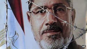 A portrait of ousted Egyptian President Mohammed Morsi is seen behind barbed wire during a demonstration by Morsi's supporters in Cairo, Egypt, Sunday, July 21, 2013.