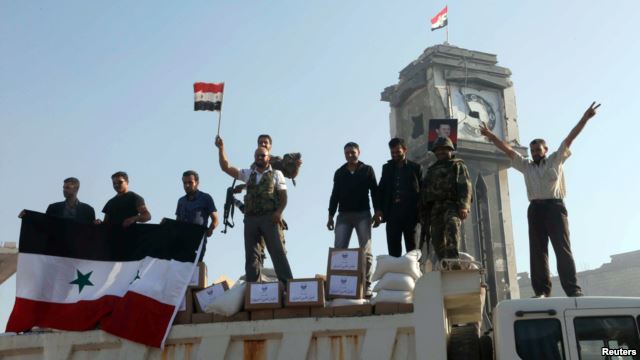 Fighters loyal to the Assad regime hold up the Syrian  national flag stand June 5, 2013 after capturing the town of Qusair from anti-government rebels.