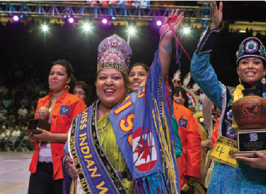 Miss Indian World Kansas K. Begaye waves to a roaring crowd. Sixteen young women from various tribes competed for the title of Miss Indian World; it is the most prominent Native pageant in North America.