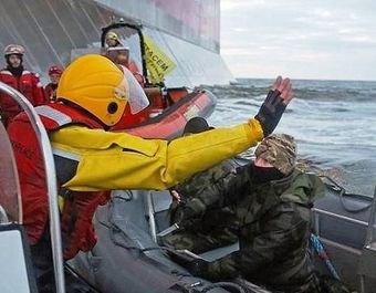 A Russian Coast guard officer points a knife at a Greenpeace activist.