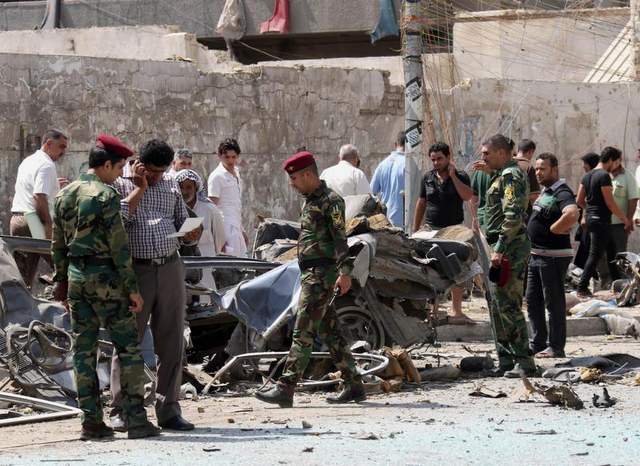 Security forces and citizens inspect the site of a car bomb attack in front of the Ministry of Higher Education and Scientific Research in Baghdad, Iraq, on Sept. 18.