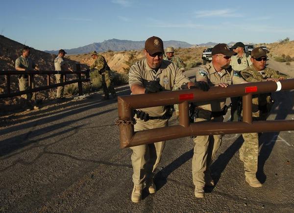 Federal law enforcement officers open a gate to allow a convoy of cattle to get through at the Lake Mead National Recreation Area near Overton, Nev. Thursday, April 10, 2014. Two people were detained while protesting the roundup of cattle owned by Cliven Bundy on the road. (AP Photo/Las Vegas Review-Journal, John Locher) AP Photo/Las Vegas Review-Journal, John Locher