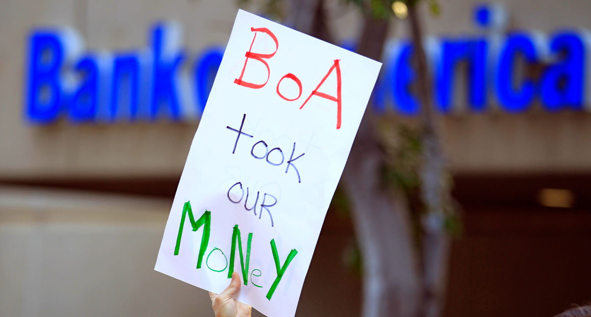 A protester holds up a sign in front of the Bank of America as a coalition of organizations march to urge customers of big banks to switch to local credit unions in San Diego California November 2, 2011.