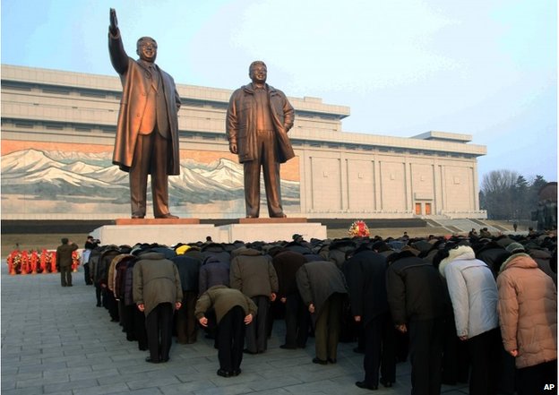 Crowds bow to the statues of North Korea's late leader Kim Jong-il, right, and his father Kim Il-sung near Pyongyang, Feb. 16