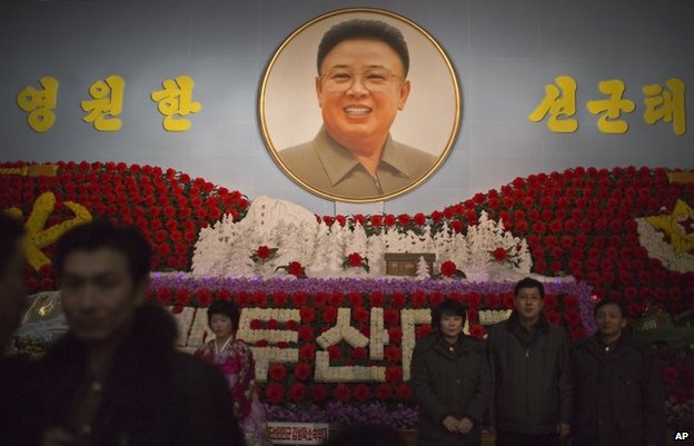 North Koreans pose for family pictures in front of a portrait of the late leader Kim Jong Il during a flower exhibition in Pyongyang, North Korea, Sunday, Feb. 16