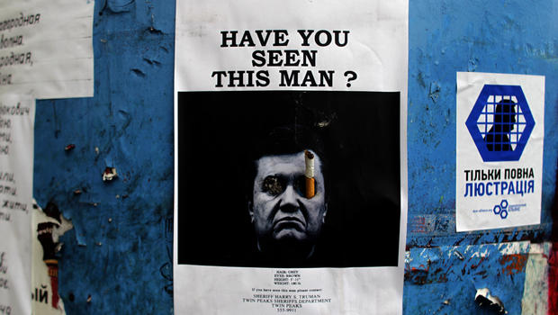 A poster with a photo of fugitive Ukrainian President Viktor Yanukovich, who fled the capital Kiev and went into hiding after months of protests against his government, is seen fixed onto a barricade in central Kiev