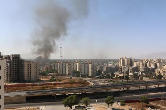 Smoke rises near buildings after heavy fighting between rival militias broke out near the airport in Tripoli July 13, 2014.   REUTERS/ Hani Amara
