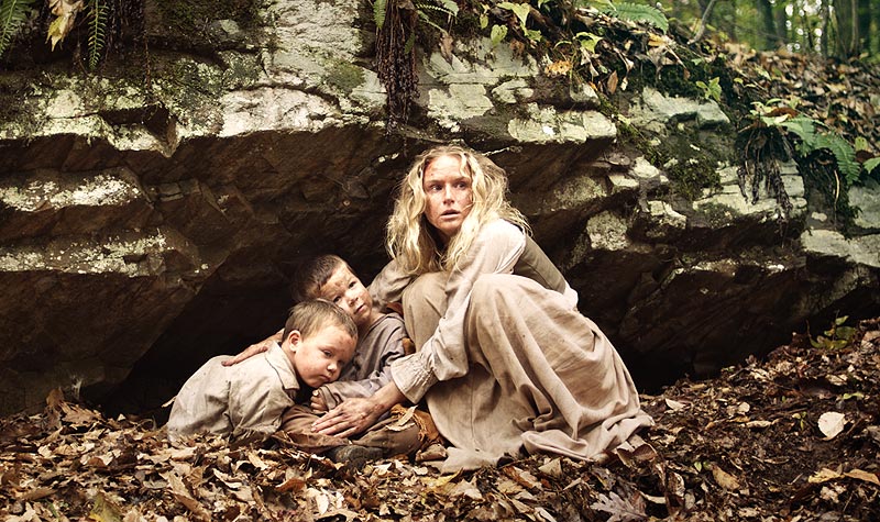 Caption from aloneyetnotalone.com: 'Lydia (Jenn Gotzon) hides two of the children after their village was attacked by Native Americans'