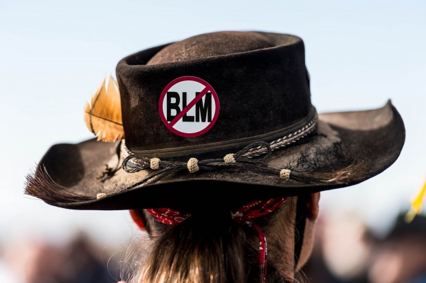 A protester, wearing an anti-Bureau of Land Management sign on his hat, listens to San Juan County Commissioner Phil Lyman at Centennial Park in Blanding, Utah on Saturday, May 10, 2014. Lyman organized an ATV protest ride into Recapture Canyon to show that the federal agency isn't the "supreme authority" and local residents have a right to have their opinions heard. The area has been closed to motorized use since 2007 when an illegal trail was found that cuts through Ancestral Puebloan archaeological sites. The canyon is open to hikers and horseback riders. (AP Photo/The Salt Lake Tribune, Trent Nelson)