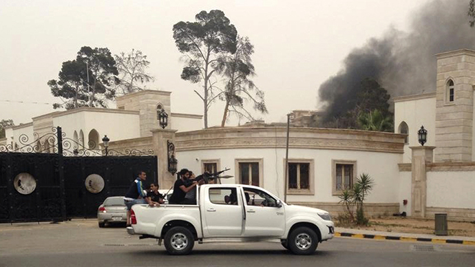 Armed men aim their weapons from a vehicle as smoke rises in the background near the General National Congress in Tripoli May 18, 2014. (Reuters)