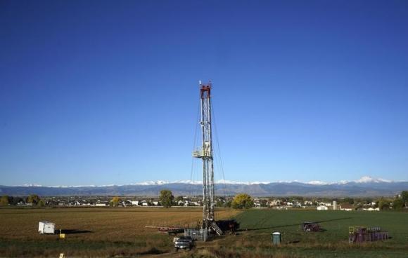 Workers drill a new oil well in a farm field within sight of houses near the town of Longmont, Colorado October 14, 2014.  REUTERS/Rick Wilking/Files
