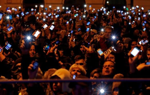 People hold up their mobile phones as they protest against a new tax on Internet data transfers in the centre of Budapest October 26, 2014. REUTERS/Laszlo Balogh