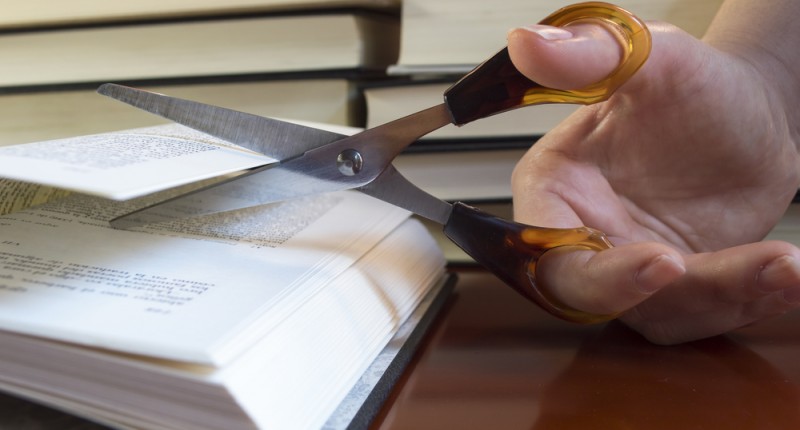 Image of scissors cutting passage out of a book, Shutterstock.com