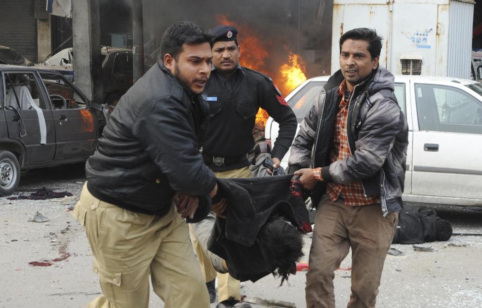 Residents and a policeman carry a dead body from the site of an explosion outside the police headquarters, in Lahore February 17, 2015. REUTERS/Imran Sheikh
