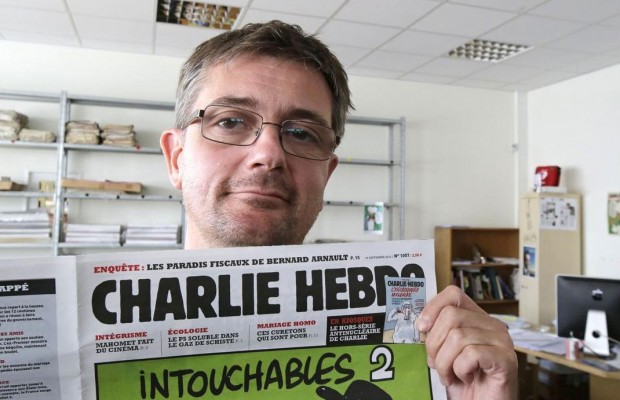 In this Sept.19, 2012 file photo, Stephane Charbonnier also known as Charb , the publishing director of the satyric weekly Charlie Hebdo, displays the front page of the newspaper as he poses for photographers in Paris. Masked gunmen shouting Allahu akbar! stormed the Paris offices of a satirical newspaper Wednesday Jan.7, 2015, killing 12 people including Charb, before escaping. It was France's deadliest terror attack in at least two decades. (AP Photo/Michel Euler, File) 