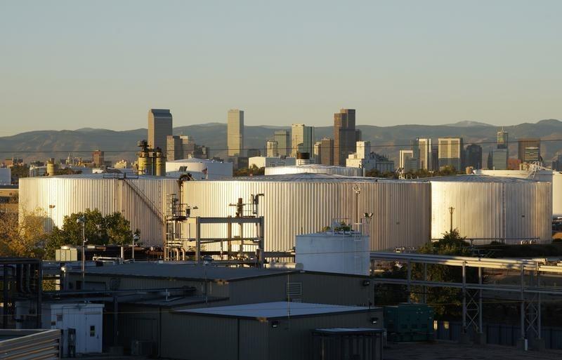 Oil storage tanks are seen at sunrise with the Rocky Mountains and the Denver downtown skyline in the background October 14, 2014.  REUTERS-Rick Wilking