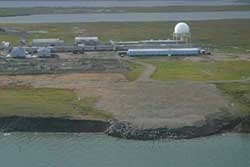 This oblique aerial photograph from 2006 shows the Barter Island long-range radar station landfill threatened by coastal erosion. The landfill was subsequently relocated further inland, however, the coastal bluffs continue to retreat.