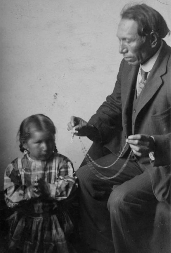 Black Elk married Katie War Bonnet in 1892 on the Pine Ridge Reservation, and they had three children. Katie converted to Catholicism, and after her death in 1903, Black Elk converted to Catholicism in 1904 and took the first name Nicholas. Pictured here is Nicholas Black Elk teaching daughter Lucy Looks Twice (born Black Elk) how to pray the rosary. Published In the land of the Wigwam: Missionary Notes from the Pine Ridge Mission by Henry Ignatius Westropp, undated (ca. 1910), p. 13. Marquette University E-Archives.