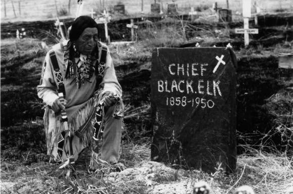 Ben Black Elk with pipe at grave of his father, Nicholas Black Elk.  Red Cloud Indian School publicity image, 1970-1971. Marquette University E-Archives.