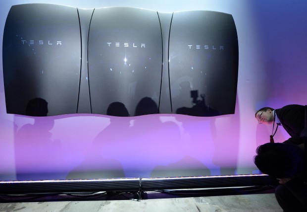 Guests pose with the Powerwall unit after Elon Musk, CEO of Tesla unveiled suit of batteries for homes, businesses, and utilities at Tesla Design Studio April 30, 2015 in Hawthorne, California. Musk unveiled the home battery named Powerwall with a selling price of $3500 for 10kWh and $3000 for 7kWh and very large utility pack called Powerpack. (Photo by Kevork Djansezian/Getty Images)