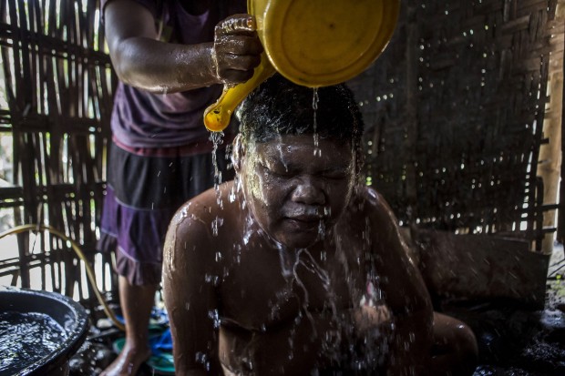 Andika, 17, who suffers from Down syndrome, takes a bath assisted by his mother Supini. He has been paralyzed and mute since he was a baby. (Photo by Ulet Ifansasti/Getty Images)