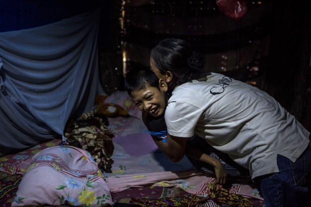Faiz is assisted by his mother Tumini, inside the house at Sidoarjo Village. (Photo by Ulet Ifansasti/Getty Images) 