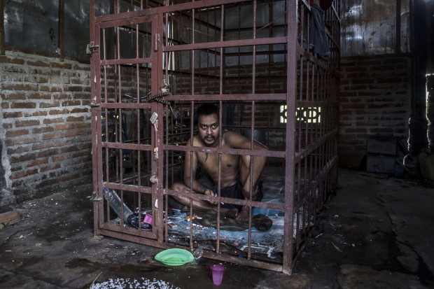 Suhananto, 30, is seen inside a cage on March 26, 2016 in in Ponorogo district, Indonesia. (Photo by Ulet Ifansasti/Getty Images)