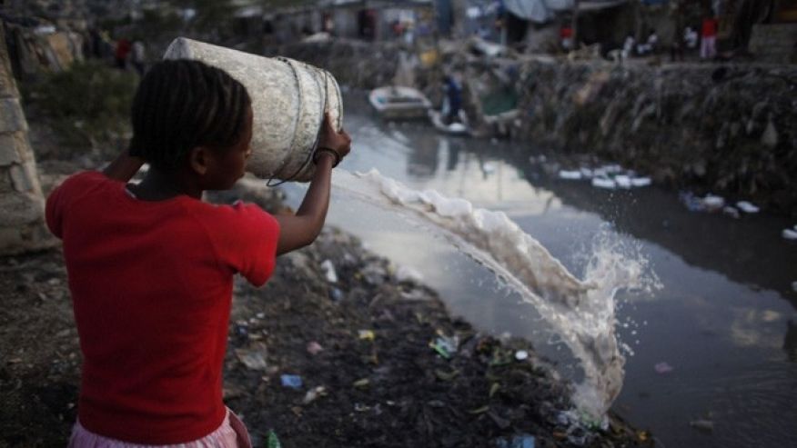 Resident throws dirty water into a drain which leads into the sea in Port-au-Prince in file photo.
