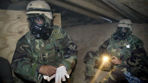 US soldiers in NBC (nuclear, biological, chemical) gear under torchlight in a bunker near camp Doha after a siren ...