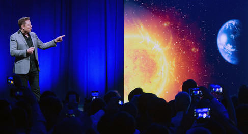 Telsa CEO Elon Musk points at the sun.