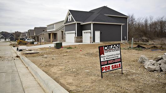 A 'For Sale' sign stands in a vacant lot near new homes in Dunlap, Illinois.
