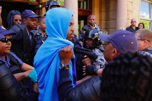 South African policemen detains a student, center, suspecting of breaking windows at the University of Cape town campus in Cape Town, South Africa, Monday, Oct. 17, 2016. (AP Photo/Schalk van Zuydam)