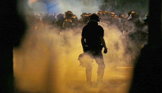 Police fire teargas as protestors converge on downtown following Tuesday's police shooting of Keith Lamont Scott in Charlotte, N.C., Wednesday, Sept. 21, 2016. Protesters have rushed police in riot gear at a downtown Charlotte hotel and officers have fired tear gas to disperse the crowd. At least one person was injured in the confrontation, though it wasn't immediately clear how. Firefighters rushed in to pull the man to a waiting ambulance.(AP Photo/Gerry Broome)