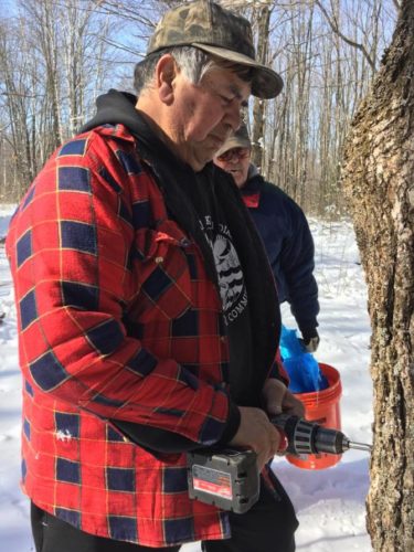 Howie Maday, 5 tastes the sap from a newly tapped maple tree during sugar bush season.